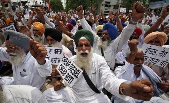 Farmers hold placards and shout anti-government slogans during a protest against the recent fuel price hike