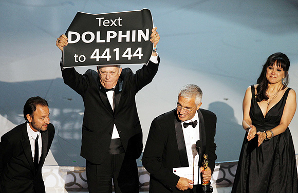Director Louie Psihoyos accepts an award with producer Fisher Stevens, producer Paula DuPre Pesman, as cast member Richard O'Barry holds up a sign after 'The Cove' won best documentary feature during the 82nd Academy Awards in Hollywood March 7, 2010