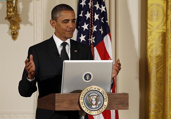 US President Barack Obama reacts after tweeting at his first ever Twitter in Town Hall in the East Room at the White House in Washington