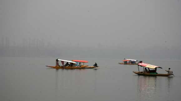 Kashmiri tourists enjoy a shikara ride as fog envelopes the Dal Lake