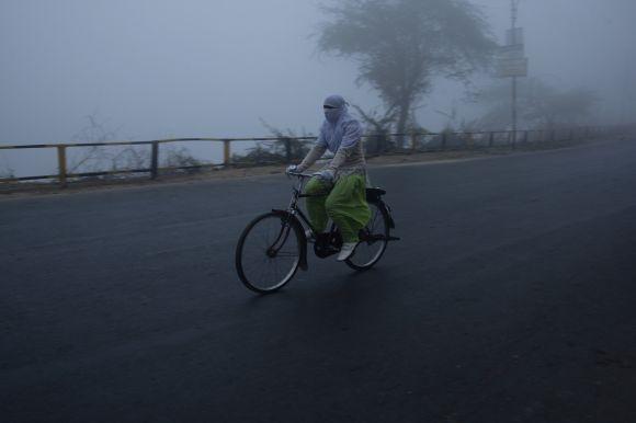 A girl cycles on a foggy and cold winter morning in Allahabad, Uttar Pradesh