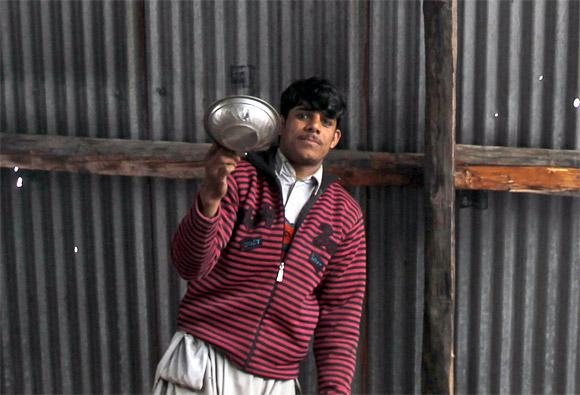 A villager stands under the roof of his house, which was damaged by shelling from Pakistani troops near the Line of Control in Churunda village, about 129 km northwest of Srinagar