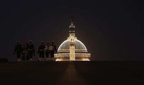 Members of the military band walk in front of the illuminated Presidential Palace after the ceremony in New Delhi