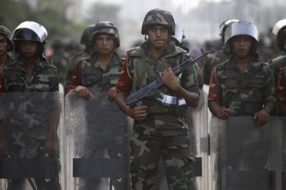 Army soldiers take their positions in front of protesters who are against Morsi, near the Republican Guard headquarters in Cairo