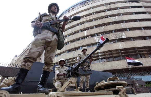 Soldiers stand on an armoured personnel carrier positioned outside the state-run television station in Cairo on Saturday