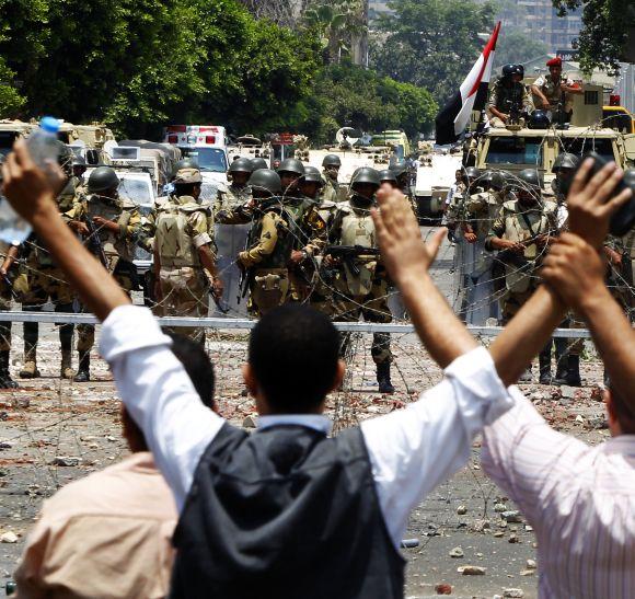 Members of the Muslim Brotherhood shout slogans in front of army soldiers at Republican Guard headquarters in Nasr City, on Monday.