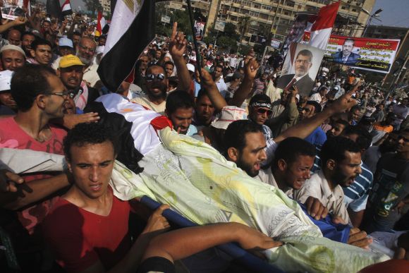 Supporters of Mursi carry the body of a fellow supporter killed in violence outside the Republican Guard headquarters in Cairo