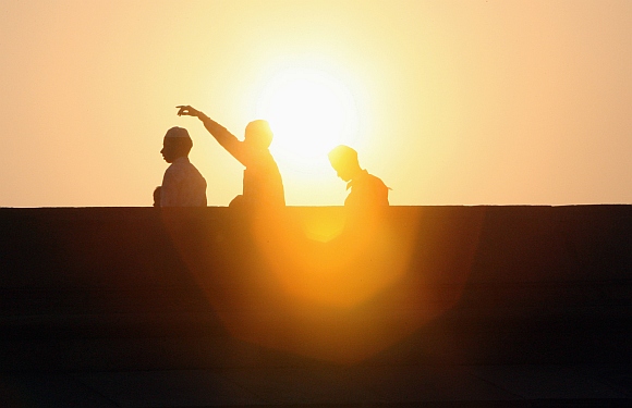 Men are silhouetted against the morning sun before offering prayersat the Jama Masjid mosque on the occasion of Eid al-Fitr in the old quarters of Delhi