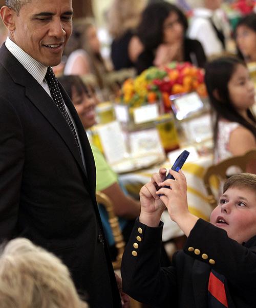 A boy takes pictures of US President Barack Obama at the second annual 'kids' state dinner', to honor the winners of a nationwide recipe challenge to promote healthy lunches, at the White House in Washington