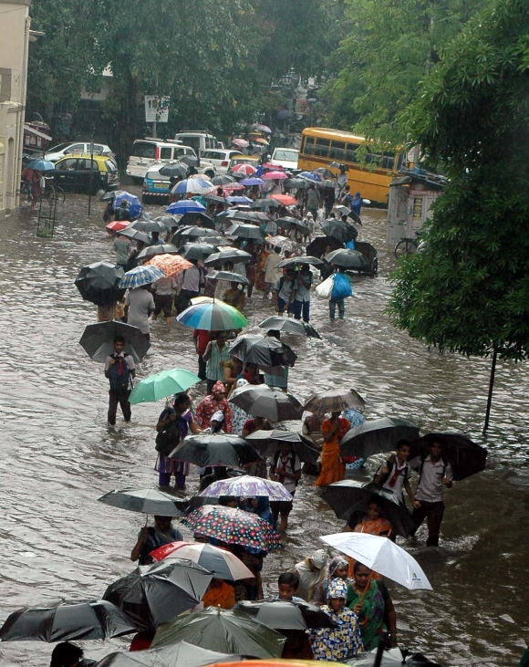 Commuters wades through a water-logged road in Dharavi, Central Mumbai