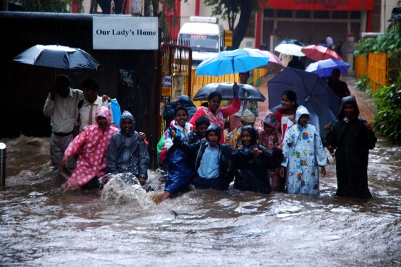 Schoolchildren and their parents struggle at a waterlogged Hindmata Chowk in Central Mumbai
