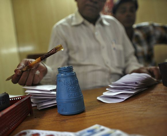 An employee uses glue as he prepares telegrams to be sent at the Central Telegraph Office in New Delhi