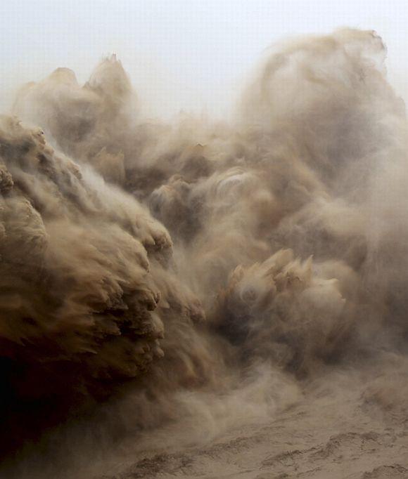 Visitors watch water gushing from the section of the Xiaolangdi Reservoir on the Yellow River, during a sand-washing operation in Jiyuan, Henan province