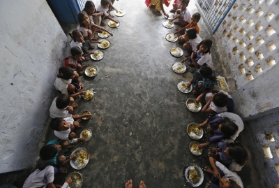 School children eat their free mid-day meal, distributed by a government-run primary school, at Brahimpur village in Chapra district
