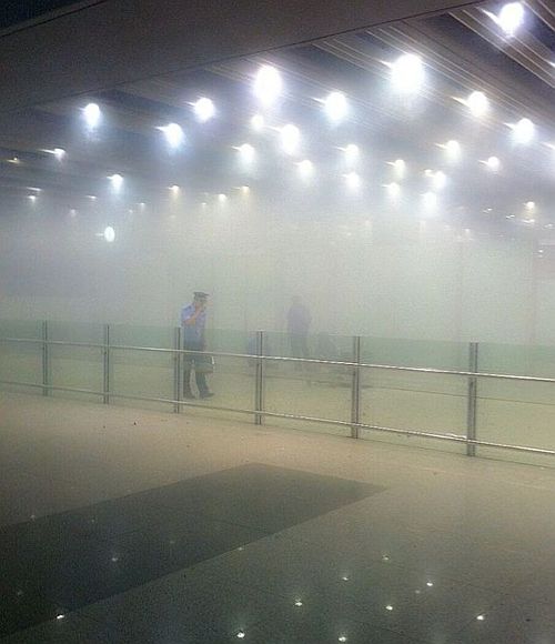 A policeman stands amid smoke at the arrival gate B after an explosion at the Terminal 3 of Beijing Capital International Airport
