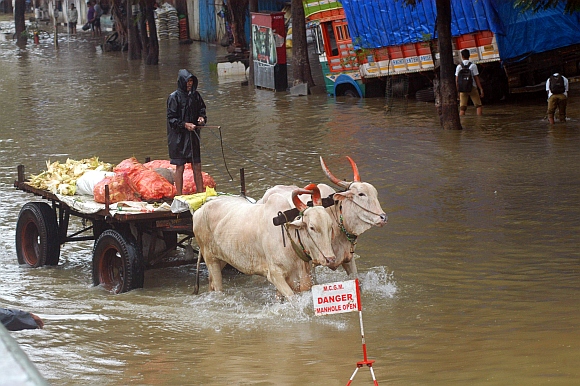 A vegetable vendor trudges through a waterlogged road at Elphinstone Road