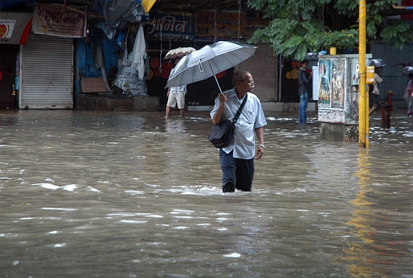 An office-goer makes slow progress as he trudges through a flooded road in Parel