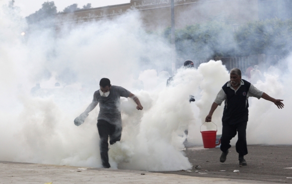 Supporters of Morsi run from tear gas fired at them by police during clashes in Nasr city area