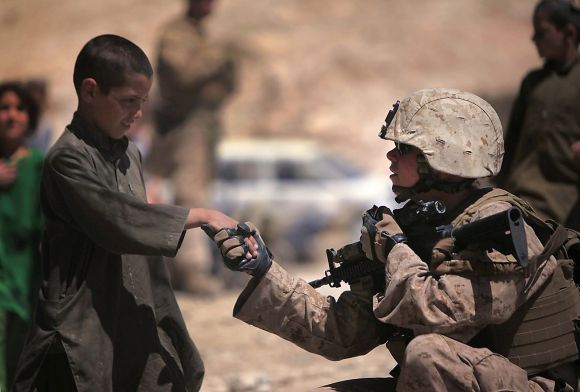 Sgt. Julie Nicholson, Female Engagement Team leader, Marine Headquarters Group, I Marine Expeditionary Force, shakes hands with an Afghan child during a mission in Helmand Province, Afghanistan