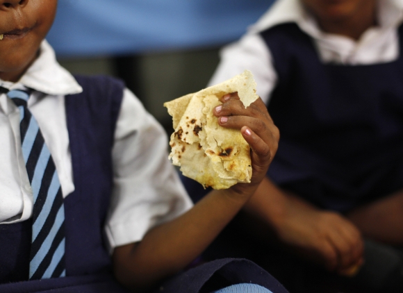 A gril eats her mid-day meal in a school in Chapra