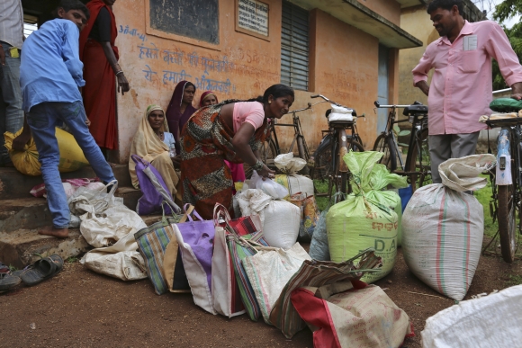 A woman ties a sack filled with subsidized food outside in Chhattisgarh