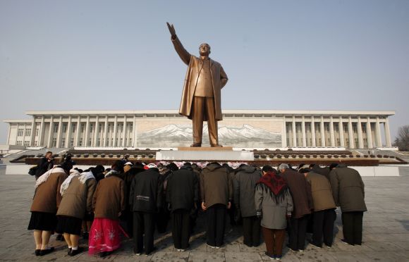 A group of people bow at the base of the giant bronze statue of the state founder and 'Great Leader' Kim-Il Sung in the North Korean capital of Pyongyang