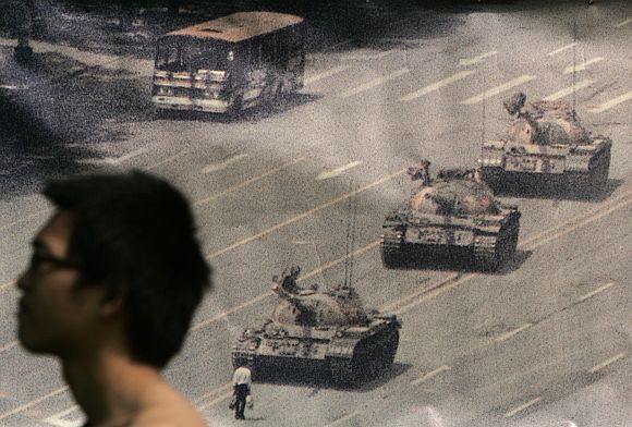 A man walks past a banner, printed with a photo of a man standing in front of tanks during the 1989 military crackdown on pro-democracy protesters around Beijing's Tiananmen Square, at Hong Kong's Victoria Park