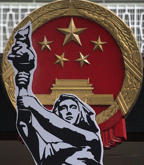 A cut-out of a poster of the Goddess of Democracy is carried by a protester past a Chinese national emblem outside the government headquarters in Hong Kong