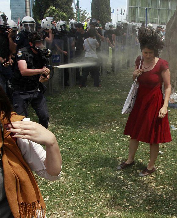 A Turkish riot policeman uses tear gas as people protest against the destruction of trees in a park brought about by a pedestrian project, in Taksim Square in central Istanbul