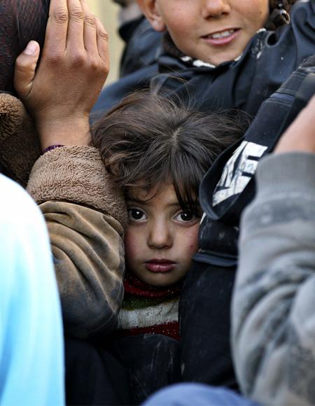 A girl looks on as she sits with other Syrian refugees fleeing violence on a Jordanian army vehicle, after crossing into Jordanian territory, near the town of Ramtha