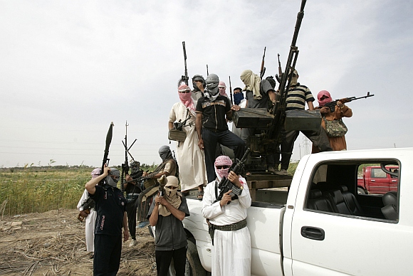 Tribal men pose with their weapons as they patrol a road north of Ramadi, 100 km west of Baghdad