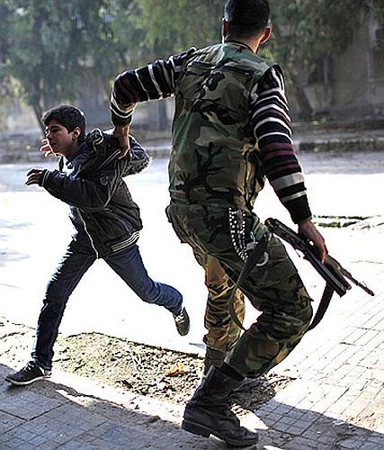 A Free Syrian Army fighter pulls a boy off the street as a sniper fires during fighting with forces loyal to Syrian President Bashar el-Assad in Aleppo city