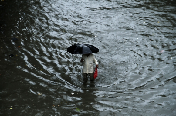 A man tries to make his way through a flooded street near Hindmata
