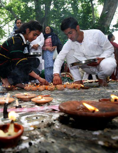 Kashmiri Pandit families light diyas while they offer prayers at Khir Bhawani temple in Tullamulla on Monday