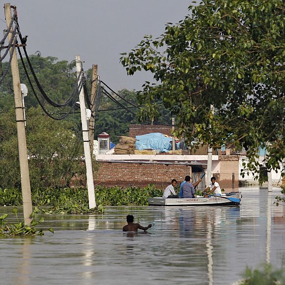 Residents use a boat to secure their belongings from a flooded colony after heavy monsoon rains caused the rise in waters of Yamuna river