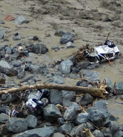 Vehicles are pictured in the flooded waters of a stream after heavy rains in Uttarakhand