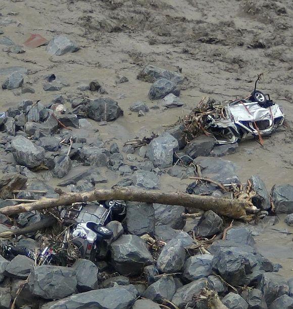 Vehicles are pictured in the flooded waters of a stream after heavy rains