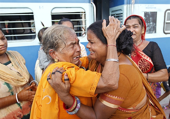 A pilgrim (in yellow) who was stranded in Uttarakhand reacts after meeting her relatives at a railway station in the western Indian city of Ahmedabad. 
