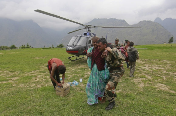 A woman is assisted by a soldier as she leaves an army helicopter during a rescue operation at Joshimat