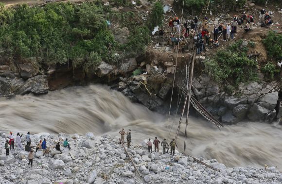 Soldiers try to repair a temporary footbridge over River Alaknanda after it was destroyed, during rescue operations in Govindghat in the Himalayan state of Uttarakhand