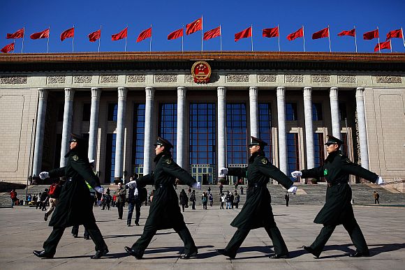 Chinese military soldiers march past the front of the Great Hall of the People after a pre-opening session of the National People's Congress
