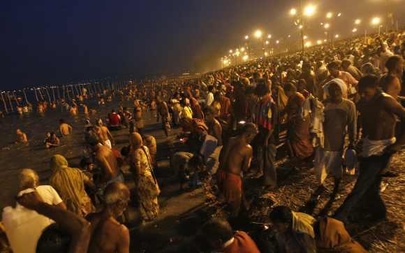 Hindu devotees gather to take a holy dip in the waters of the river Ganges during the early morning on the last bathing day of Kumbh Mela in Allahabad