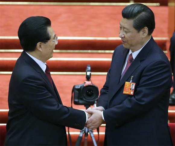 Xi Jinping shake hands with China's former President Hu Jintao during the fourth plenary meeting of the National People's Congress at the Great Hall of the People in Beijing