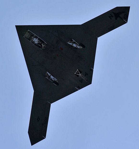 An X-47B Unmanned Combat Air System demonstrator passes over the flight deck