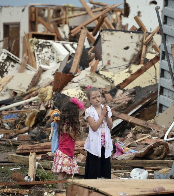 Two girls stand in rubble after a tornado struck Moore, Oklahoma