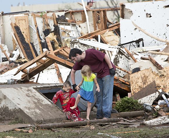 A man and two children walk through debris after the huge tornado struck Moore