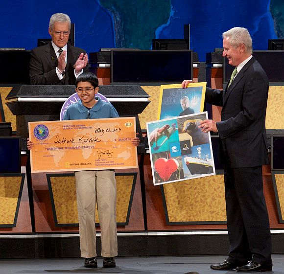 National Geographic Bee winner Sathwik Karnik, 12, of Massachusetts receives his first-place prize of a $25,000 college scholarship from National Geographic Chairman and CEO John Fahey