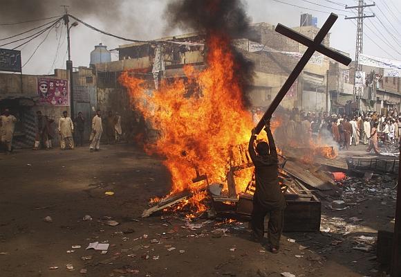 A demonstrator burns a cross during a protest in the Badami Bagh area of Lahore