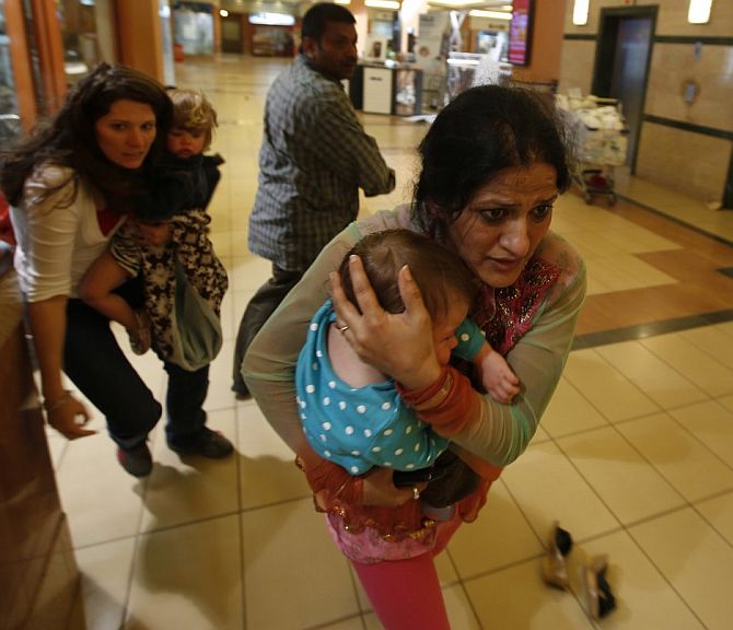 Women and children run for safety as security forces provide cover during the Nairobi Westgate Mall siege.