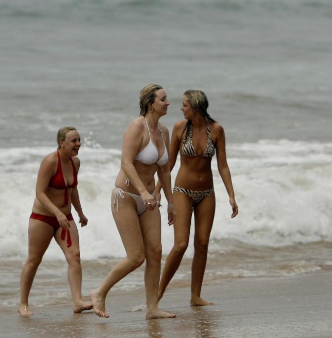 Tourists walk back after swimming at the Anjuna beach in Goa